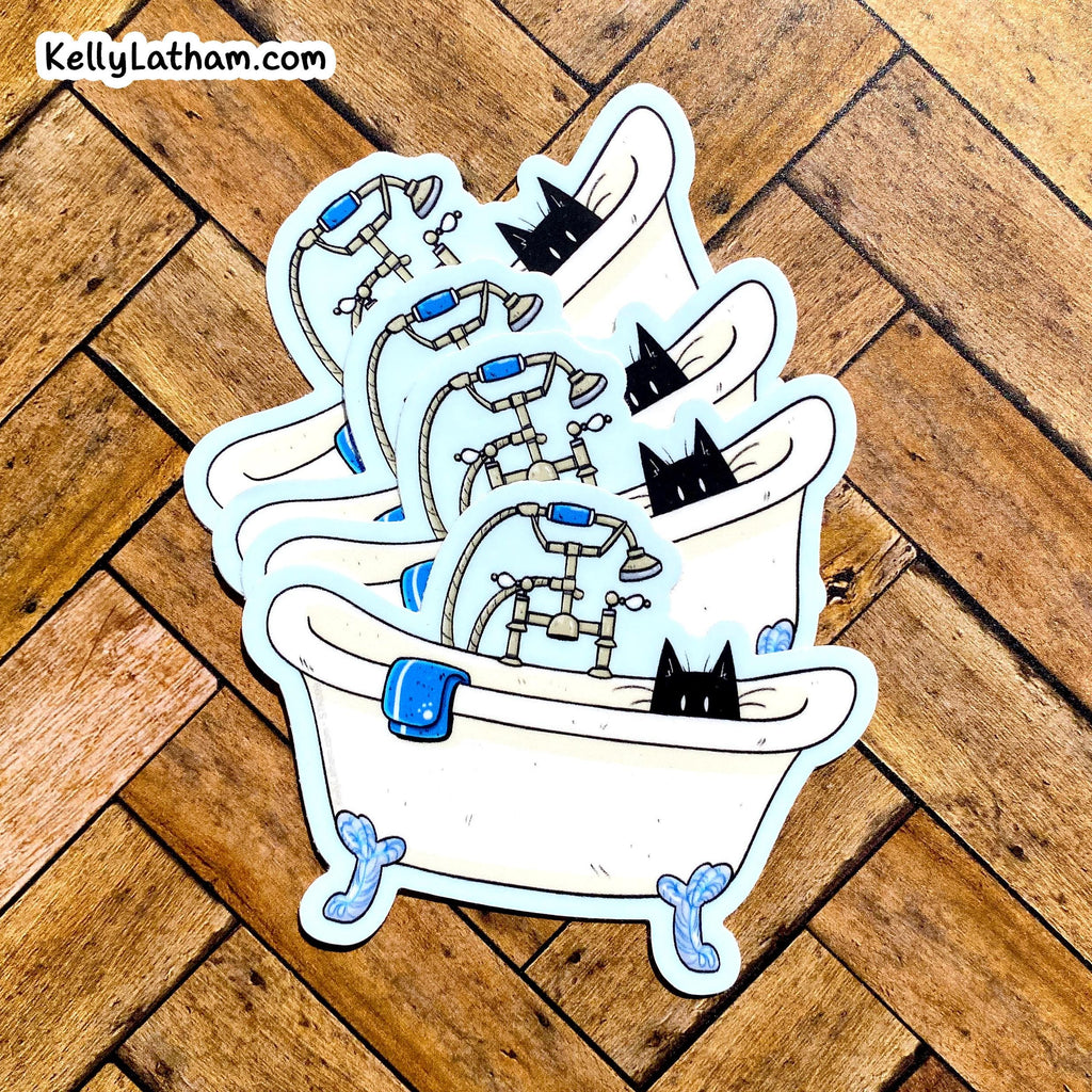 A stack of three die-cut stickers featuring a cartoon bathtub scene with black cats, shown on a wooden parquet floor. The top-left corner features the brand watermark 'KellyLatham.