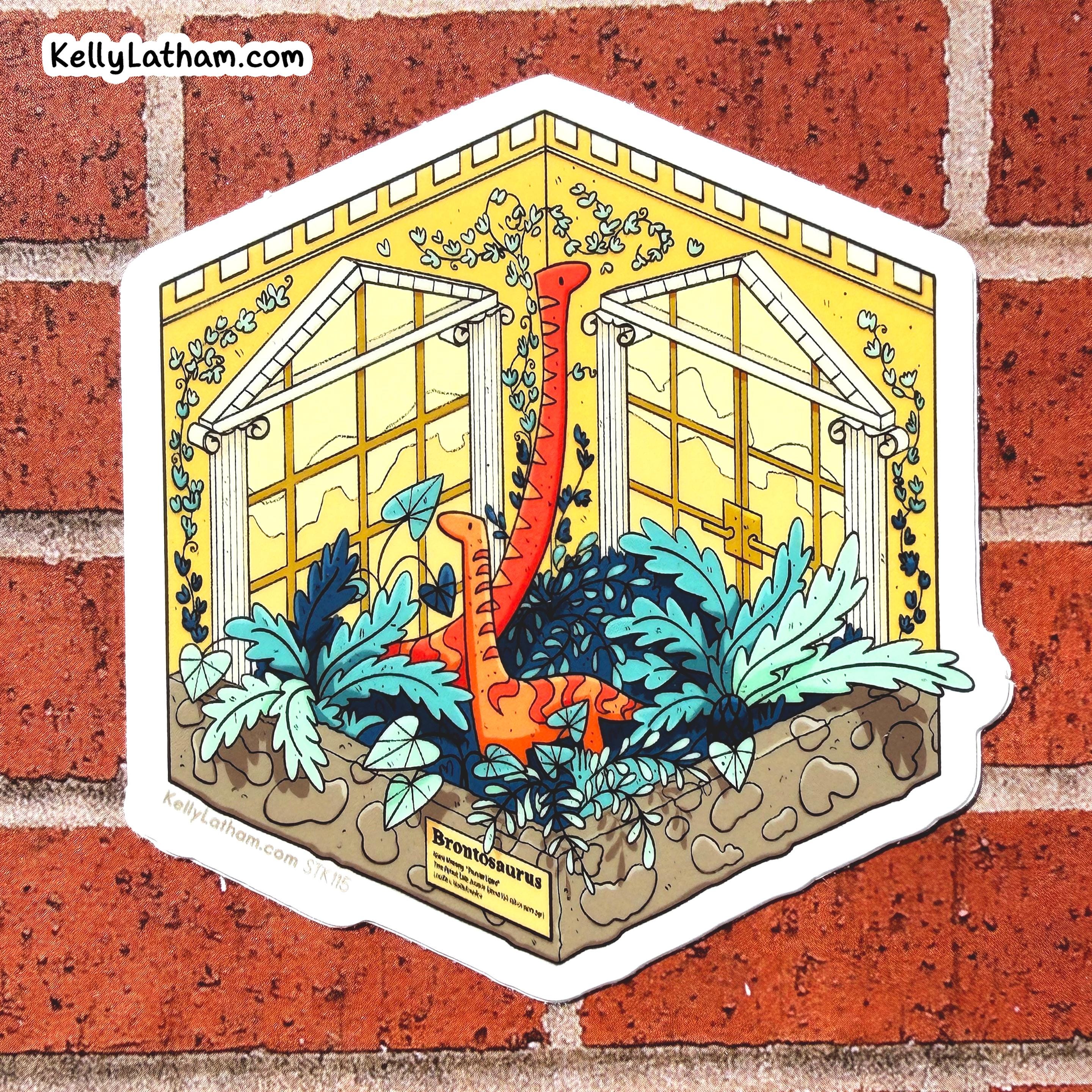 A die-cut sticker featuring an illustrated greenhouse scene with two orange long-necked dinosaurs among blue and green plants, shown against a red brick wall. The sticker has a white border and the text 'KellyLatham.