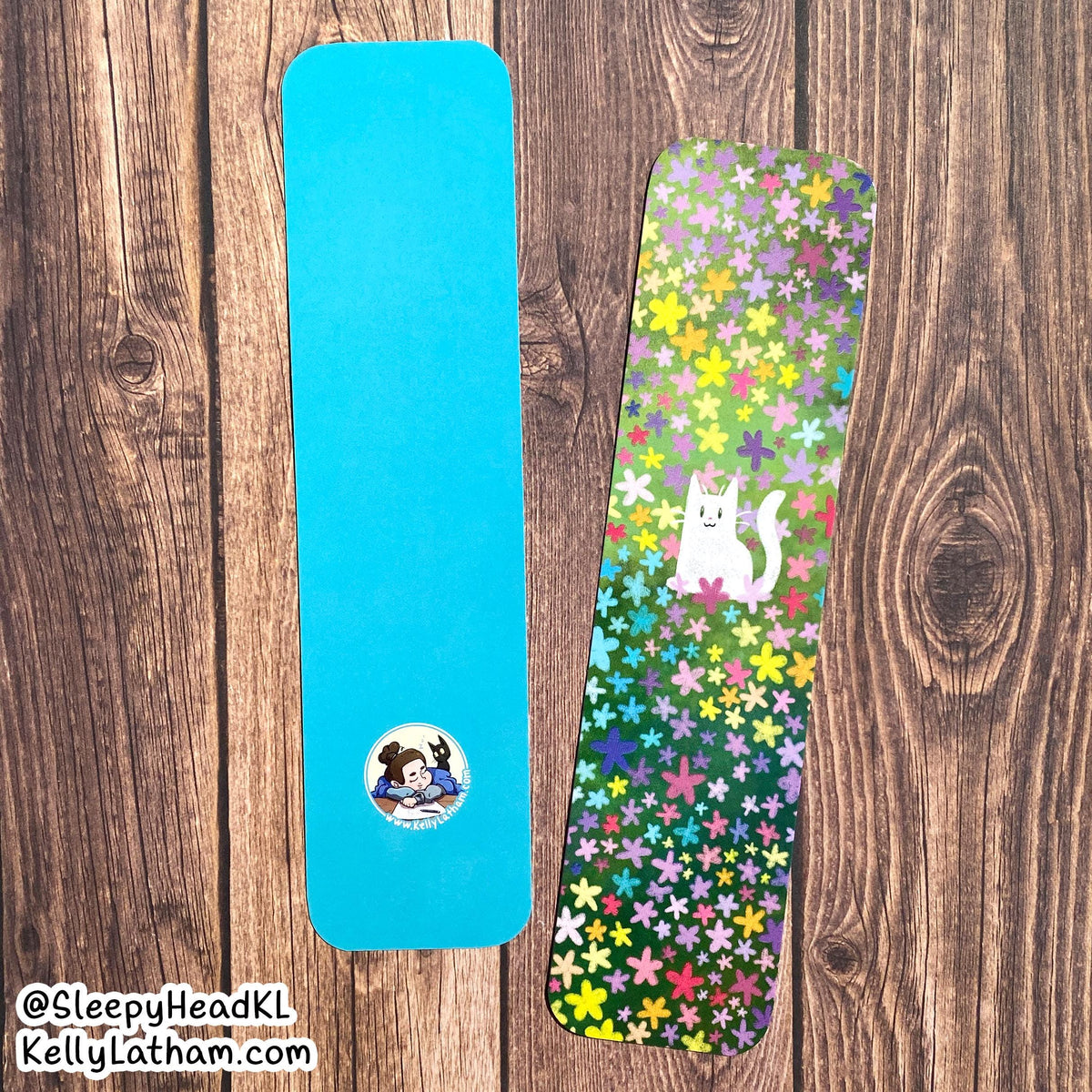 Two yoga mats displayed side-by-side on a dark wood background. The left mat is a solid bright blue with a small circular cartoon logo near the bottom.