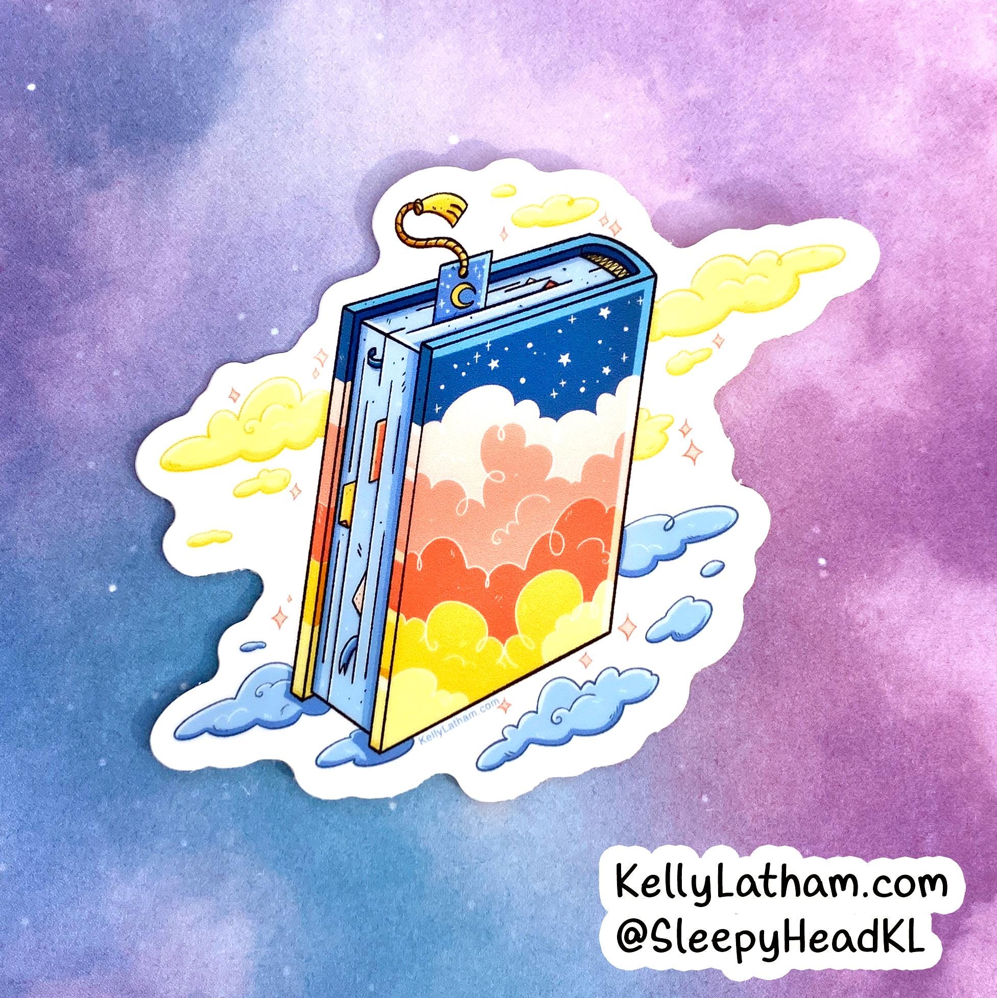 A die-cut sticker featuring a whimsical illustrated open book with a starry blue sky cover and pastel clouds inside, shown on a purple and blue watercolor background. The sticker has a white border and includes the text 'KellyLatham.