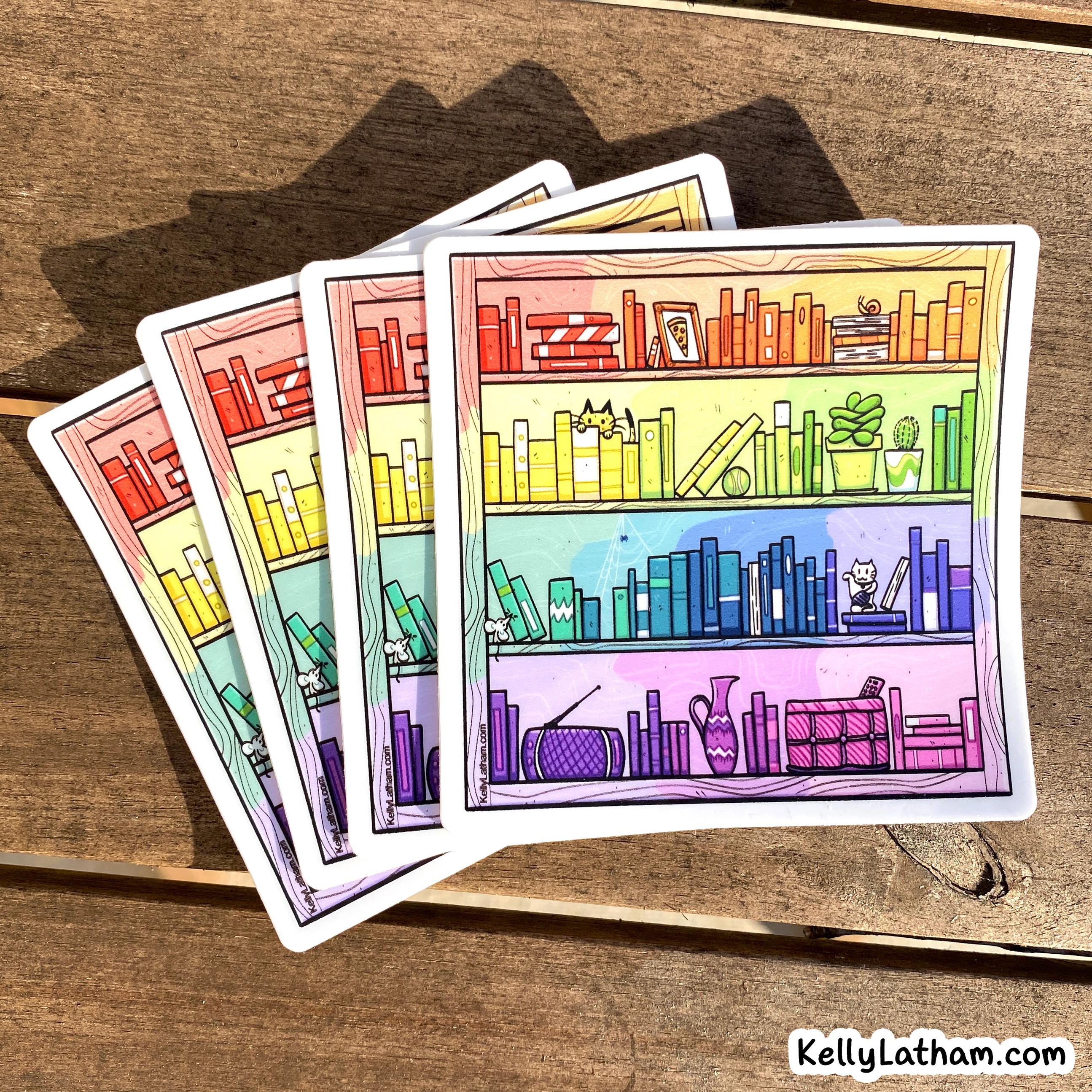 Four illustrated bookshelf stickers with a rainbow gradient are fanned out on a wooden tabletop. The artwork shows colorful books, plants, and small objects, with the brand name KellyLatham.