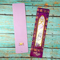 Two bookmarks on a wooden surface, one purple with a cat illustration and the other with a stained glass design.