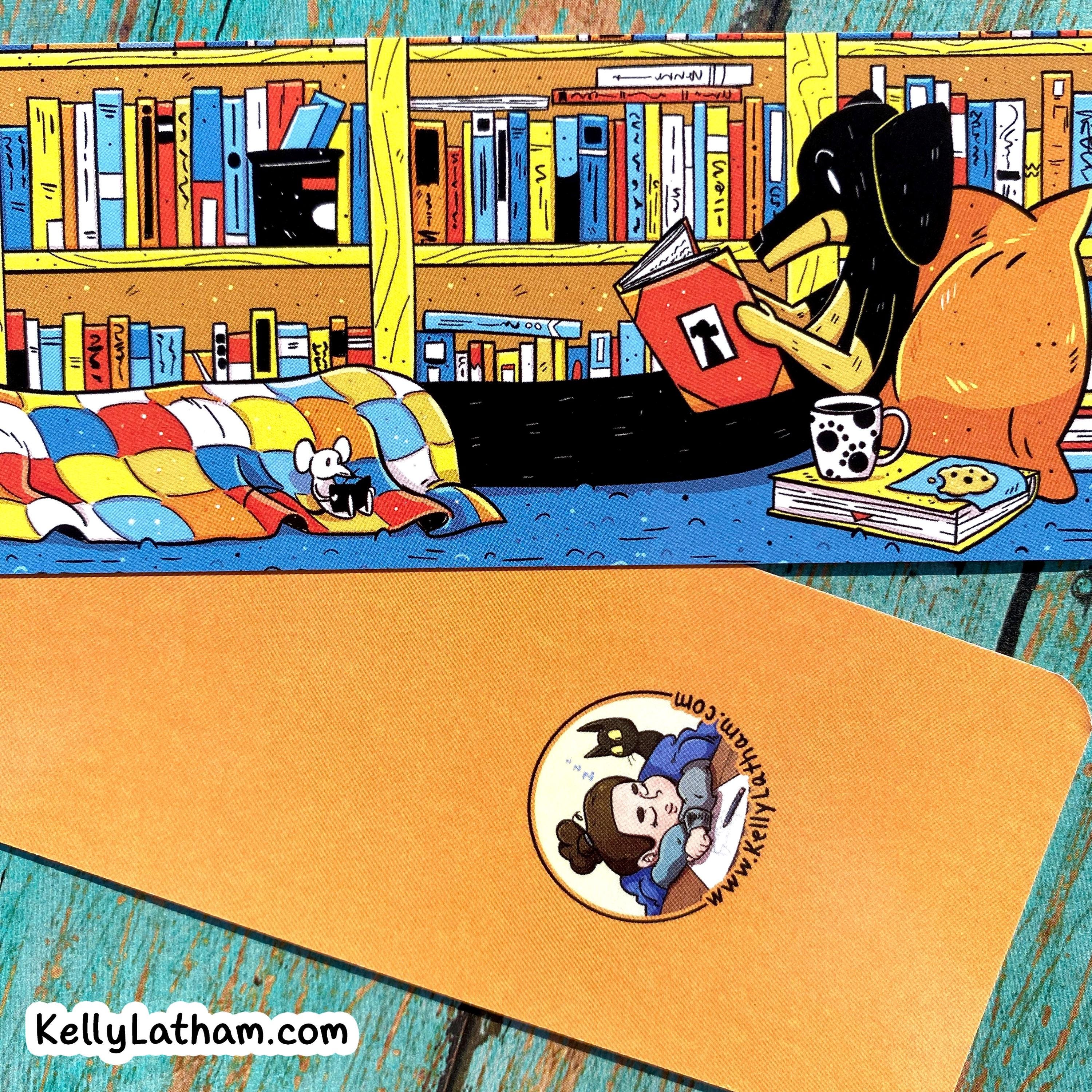 A tan rectangular product, likely a mat or pad, shown in the foreground with a circular printed sticker featuring a cartoon character and the text 'B A DAD DAD JUNE 13TH 2011'. Behind it is a colorful illustrated scene of a black dog reading a book in a library with bookshelves and a bed.