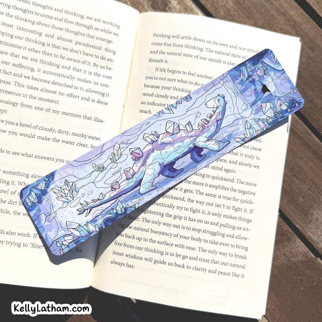A blue and white patterned wooden pencil with a floral illustration lies on top of an open book. The pencil has a blue handle with white floral and leaf designs, and a silver metal tip.