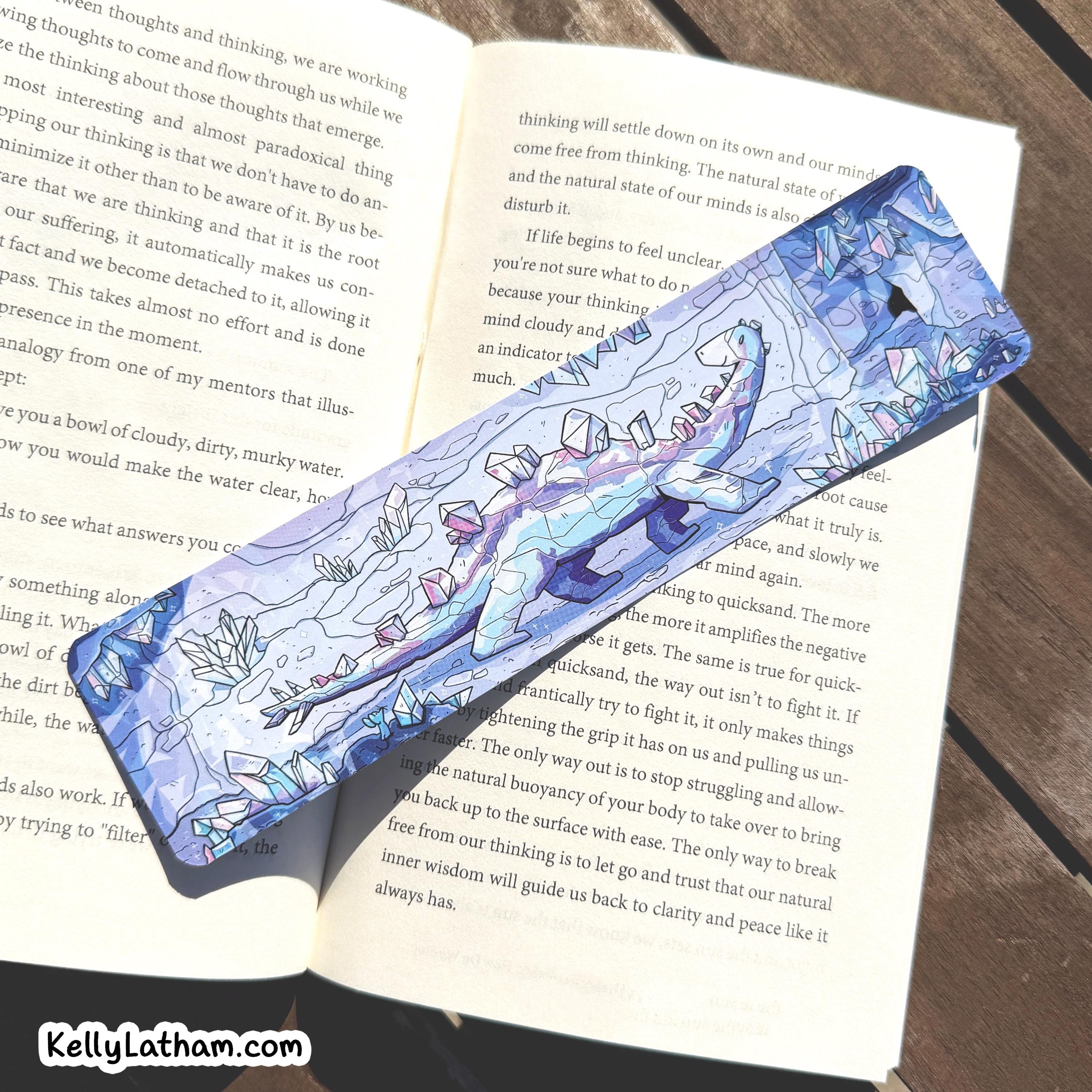 A blue and white patterned wooden pencil with a floral illustration lies on top of an open book. The pencil has a blue handle with white floral and leaf designs, and a silver metal tip.