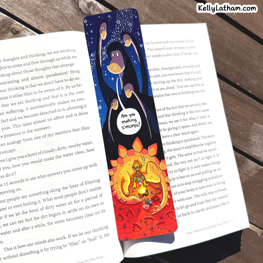 A double-sided book divider or bookmark featuring a cartoon cat illustration, shown resting on an open book. One side depicts a dark blue night sky with a sleeping cat under a starry sky, and the other side shows a bright red background with a fiery cat illustration.