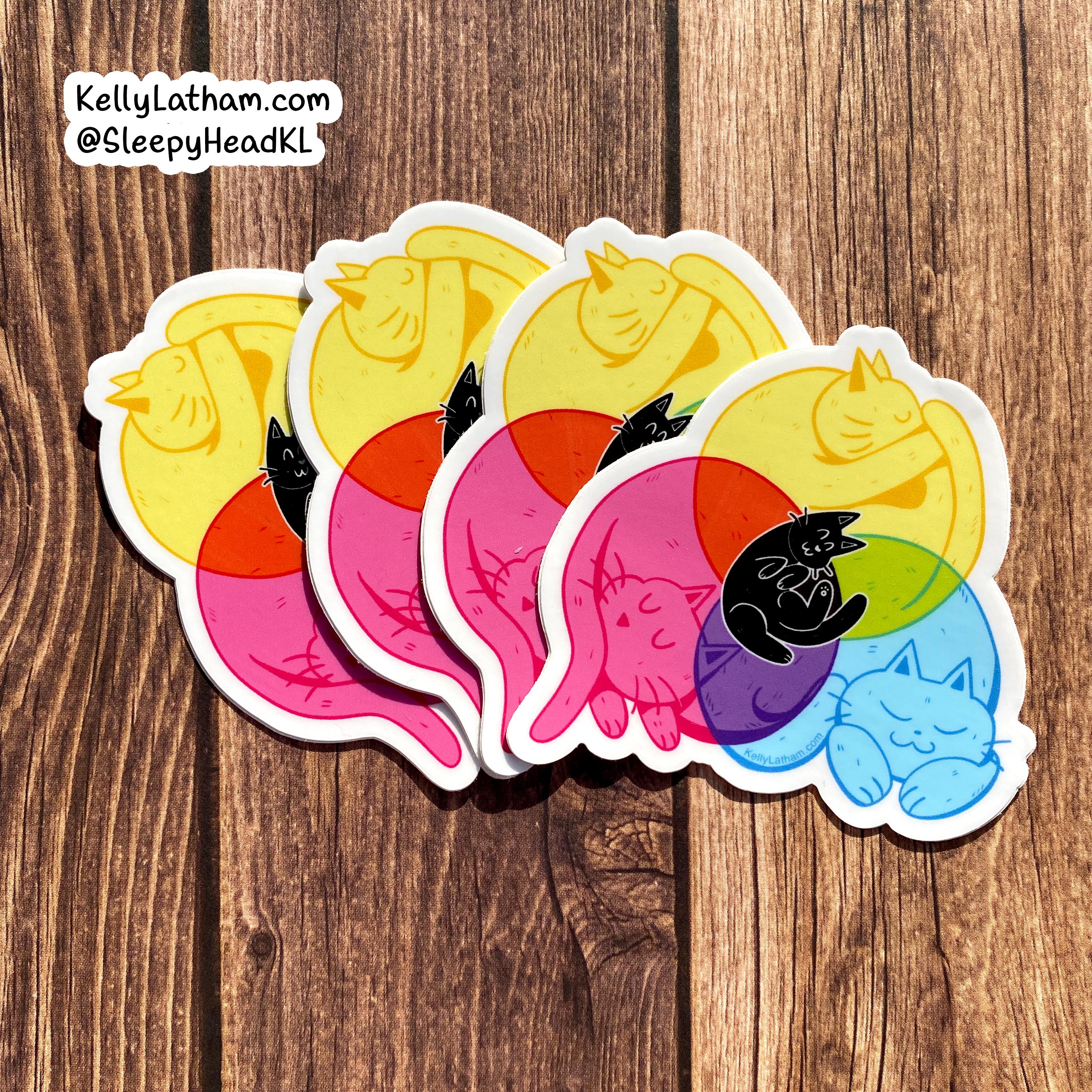 Four die-cut vinyl stickers featuring a colorful cartoon cat illustration, arranged in a fan shape on a brown wooden background. The sticker design shows a sleeping cat in a yellow crescent moon with overlapping pink, red, purple, green, and blue crescents, plus a small black cat on top.