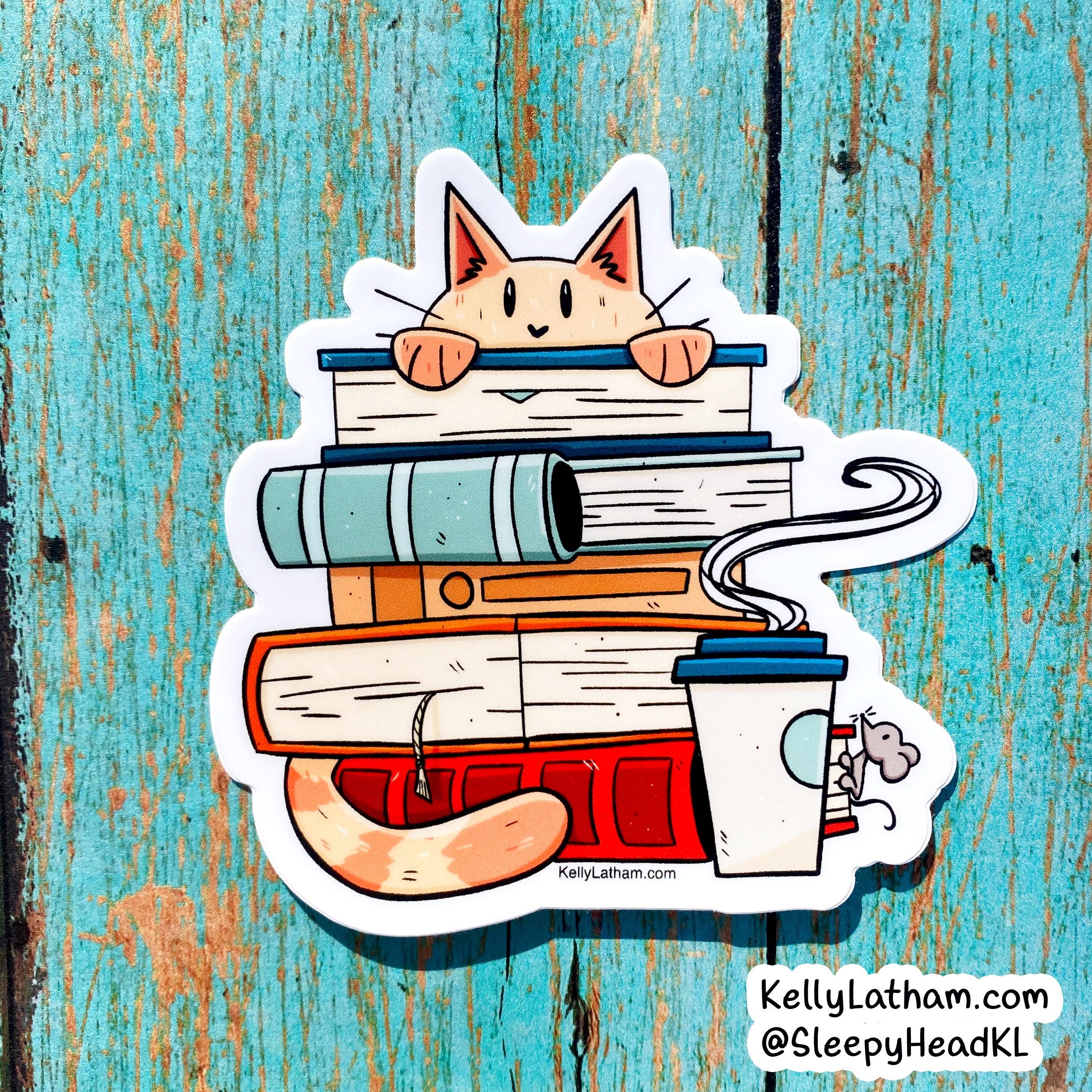 A die-cut sticker featuring a cute cartoon cat peeking over a stack of books, with a coffee cup and steam, shown on a distressed turquoise wooden background. The sticker includes the text 'KellyLatham.