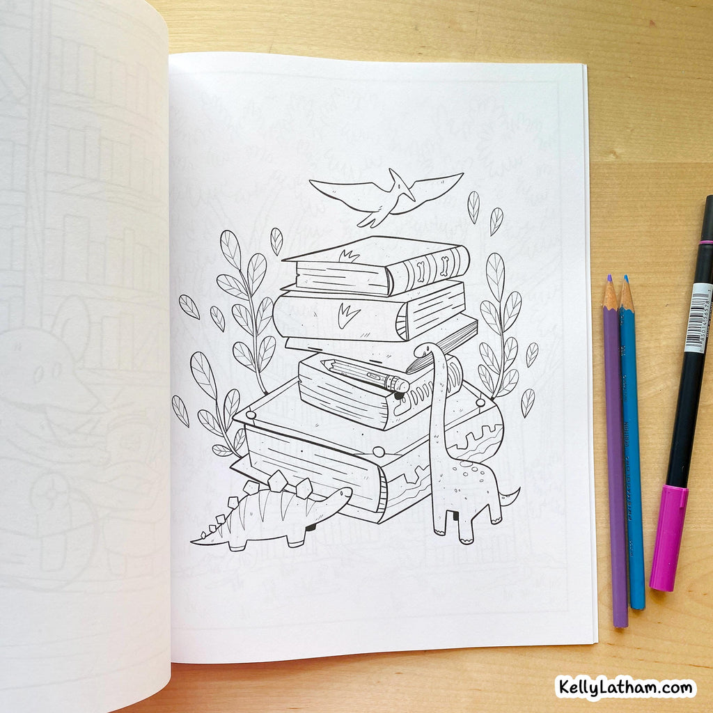 An open coloring book or journal on a wooden table, showing a black-and-white line art illustration of stacked books, dinosaurs, leaves, and a bird. Three colored pencils and a marker are placed to the right.