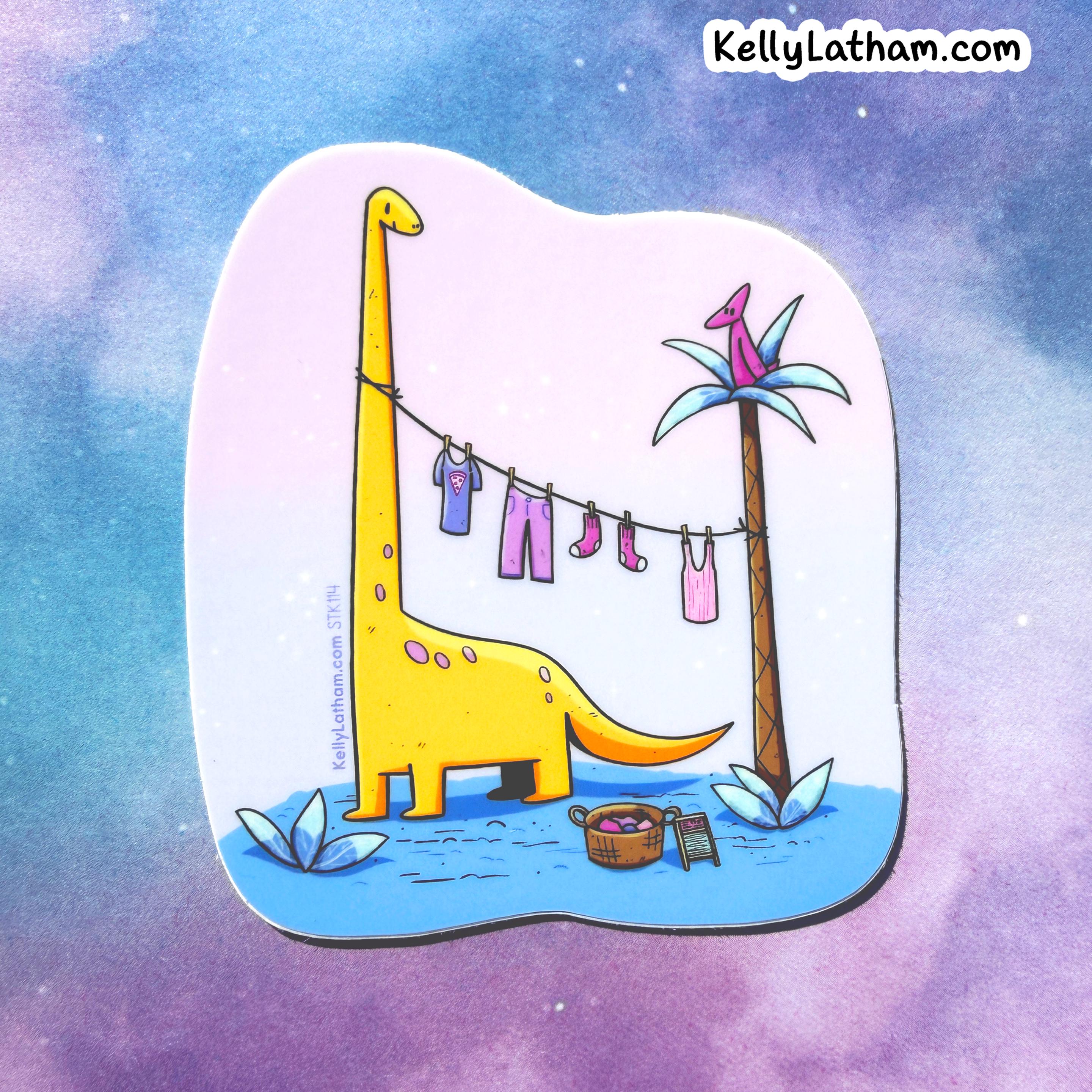 A die-cut sticker featuring a whimsical cartoon illustration of a yellow dinosaur drying laundry on a clothesline next to a palm tree, shown against a pastel purple and blue watercolor background. The brand name KellyLatham.
