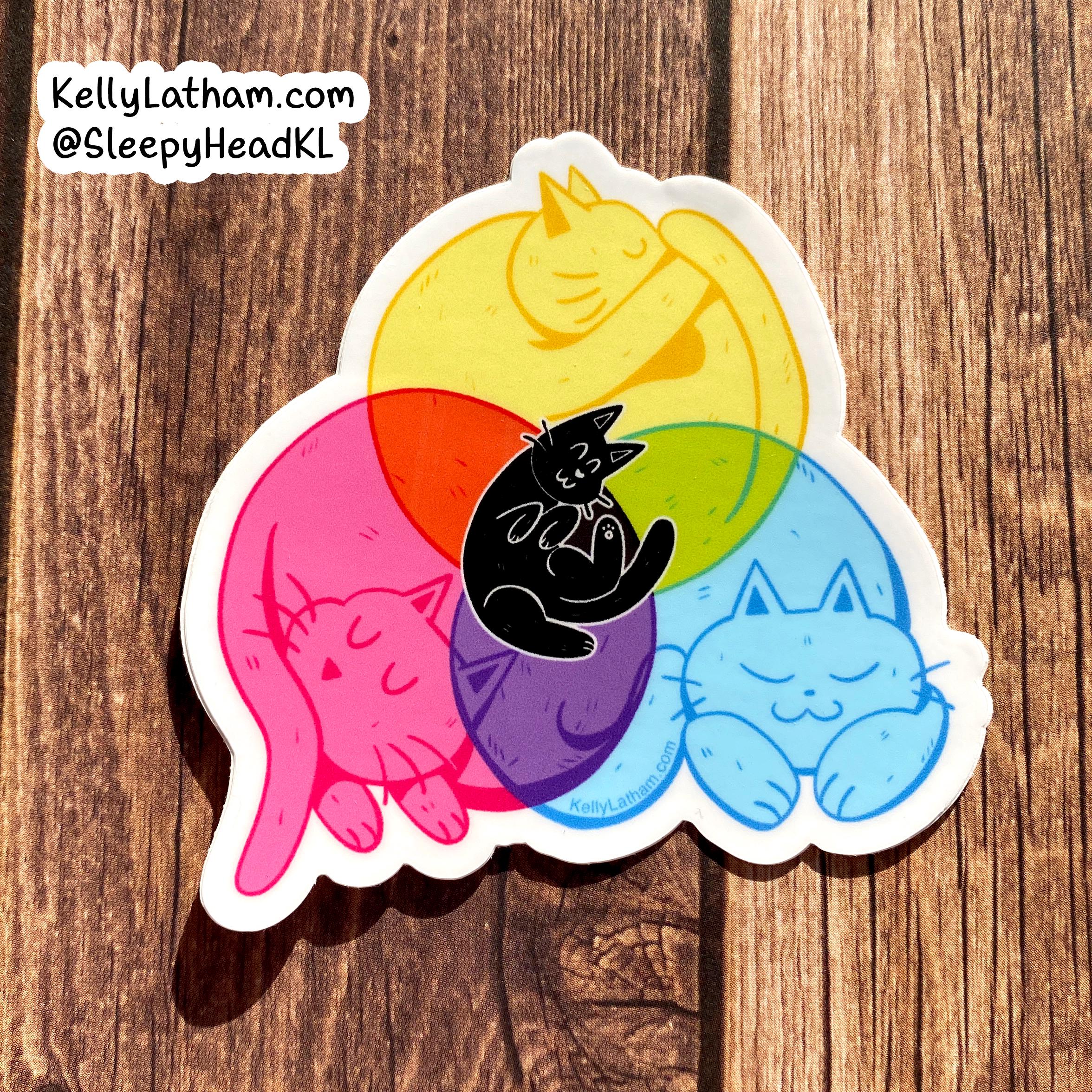 A die-cut sticker featuring four stylized sleeping cats in pink, yellow, blue, and purple, with a small black cat layered in the center, shown on a brown wood background. A seller watermark in the top left reads KellyLatham.