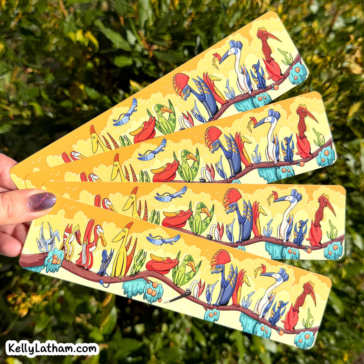Four rectangular cards fanned out in a hand, featuring a colorful illustration of birds perched on branches against a yellow background, with green foliage behind them.