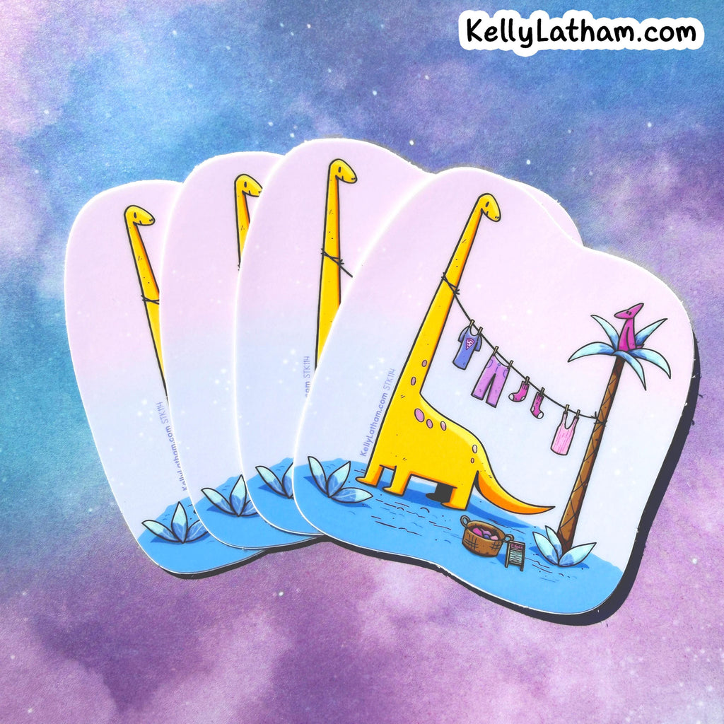 Four die-cut coasters with rounded corners fanned out, featuring a whimsical illustration of a yellow long-neck dinosaur hanging laundry on a clothesline next to a palm tree, set against a purple and blue galaxy background. The brand name KellyLatham.