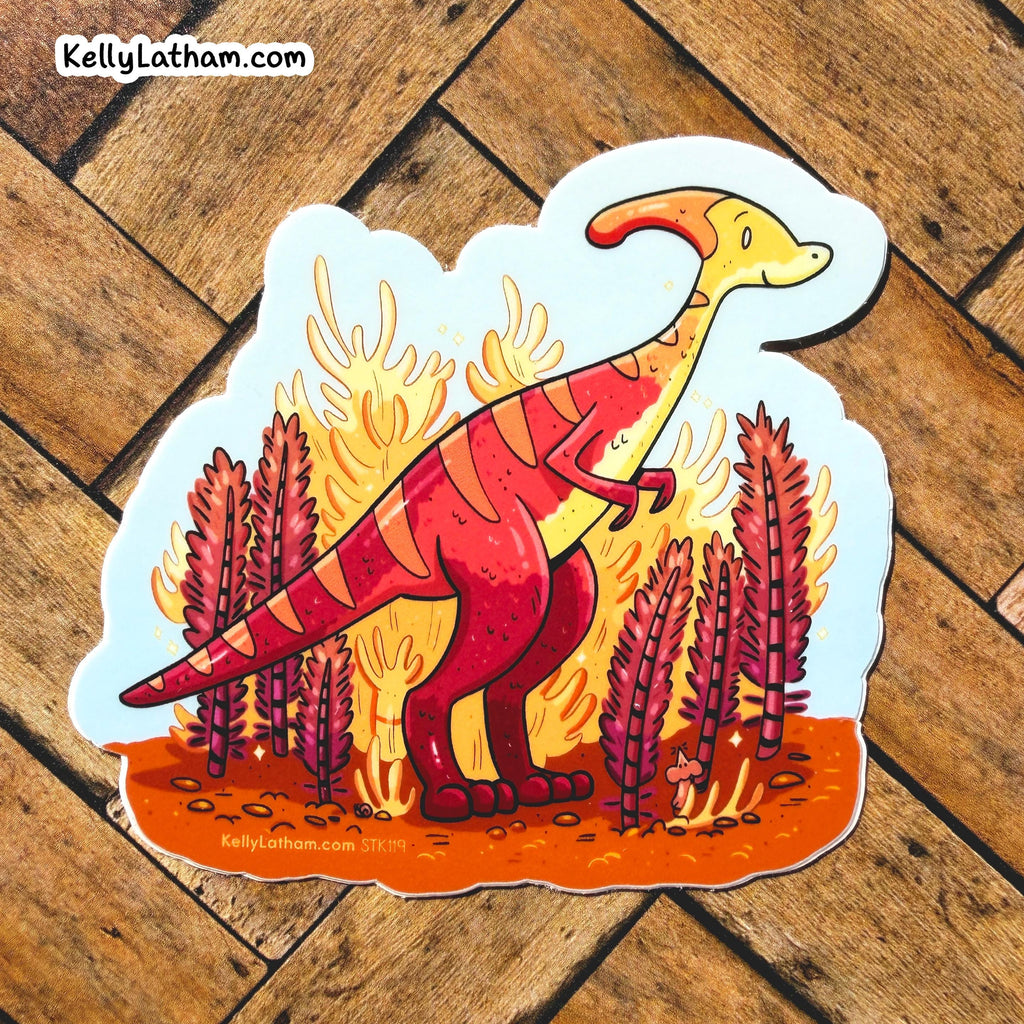 A die-cut sticker featuring a cartoon paratherept dinosaur in red and yellow stripes standing in front of orange flames and reddish plants, placed on a brown wood plank background. The sticker has the brand name KellyLatham.