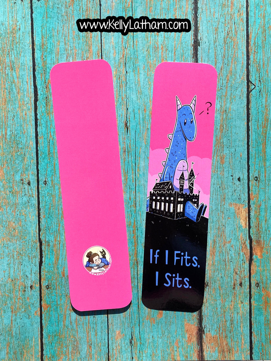 Two bright pink rectangular bookmarks displayed on a distressed turquoise wooden surface. One bookmark is plain pink with a small circular cartoon sticker near the bottom.