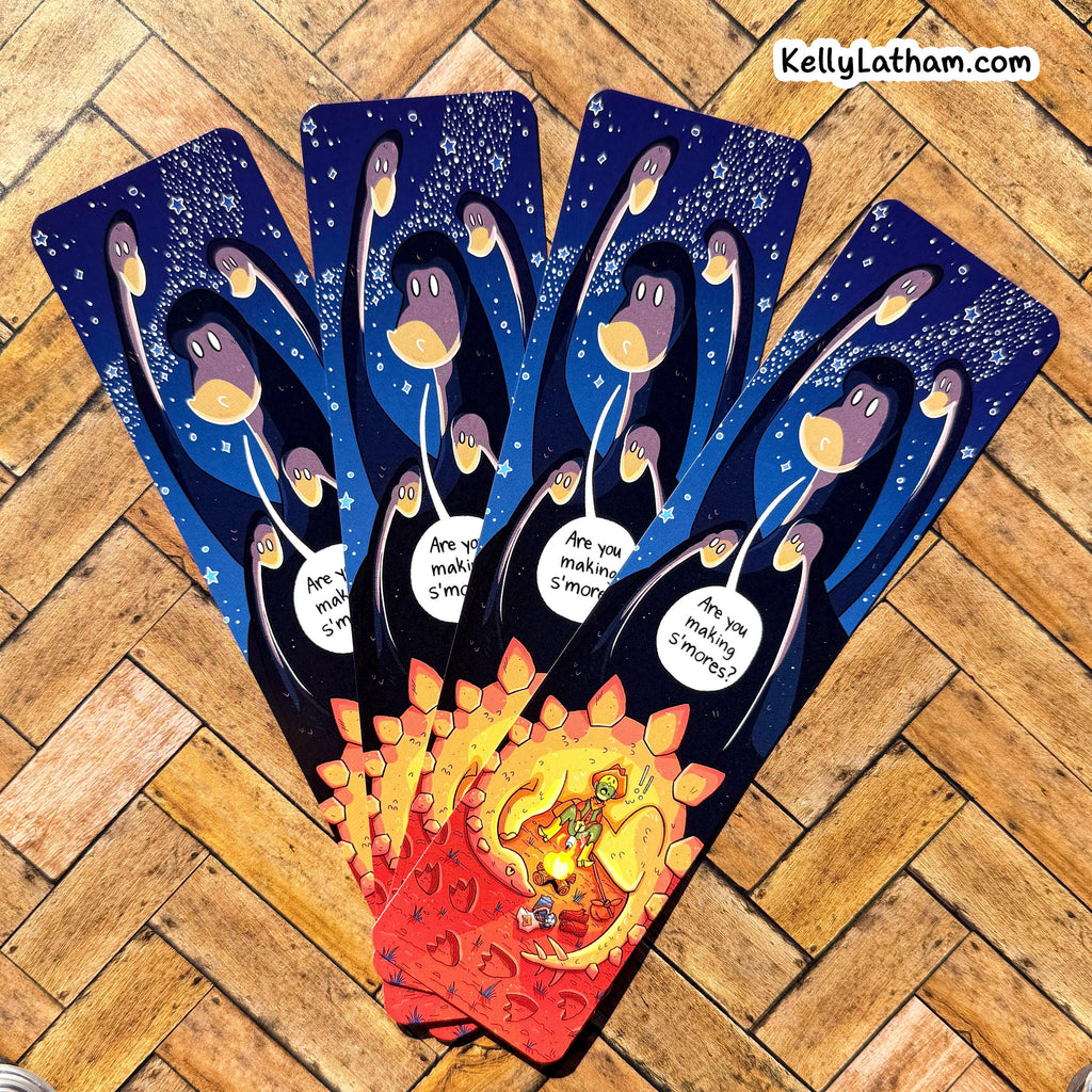 Four illustrated tarot cards fanned out on a wooden floor. The cards feature a dark blue night-sky design with stylized figures holding glowing globes, and a fiery red-orange lower section with a small golden figure.