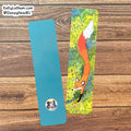 Two rectangular bookmarks on a wooden surface: one plain turquoise blue with a small circular sticker near the bottom, and one illustrated in a woodland scene featuring a fox, green foliage, and yellow flowers. A Shopify watermark is visible in the top left.