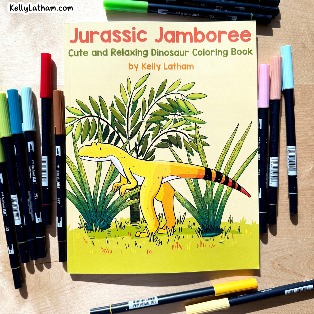 Jurassic Jamboree coloring book by Kelly Latham, featuring a yellow dinosaur illustration on the cover, surrounded by multiple colored markers on a light wood surface.