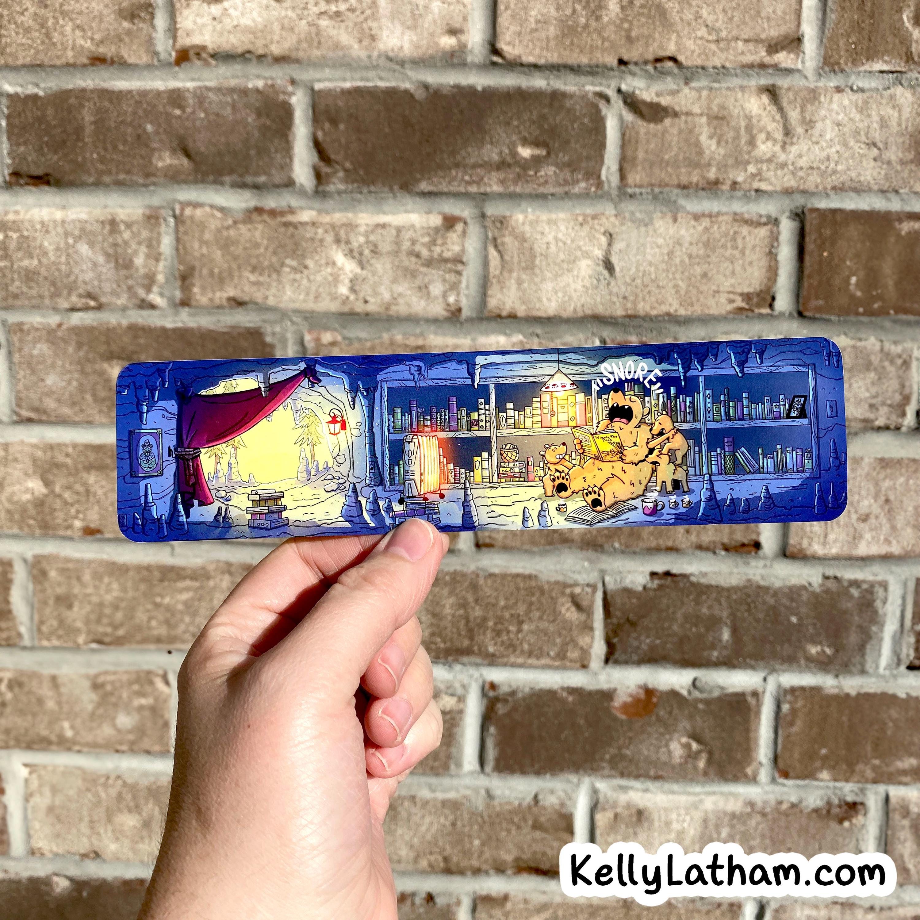 A hand holds a long, narrow blue translucent object with a detailed illustrated scene printed across it, set against a brick wall background. The object appears to be the product being sold, and a visible watermark reads KellyLatham.
