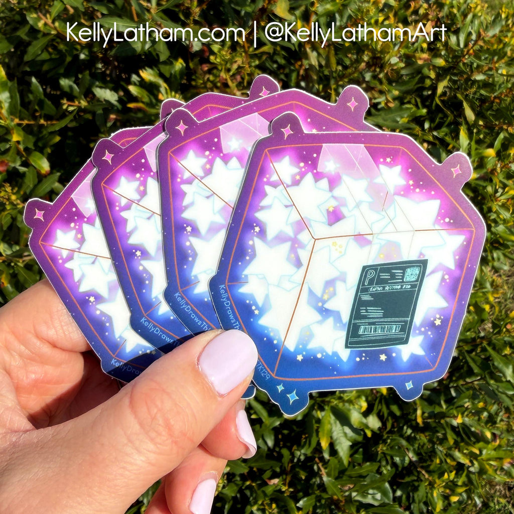 A hand holds a fan of holographic die-cut stickers featuring a purple and blue starry space design with a small green spaceship graphic, set against a background of green foliage. A watermark at the top reads 'KellyLatham.