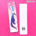 Two decorative bookmarks on a bright pink background. The left bookmark is printed with a whimsical illustration of a dinosaur in a starry blue and purple sky with clouds.