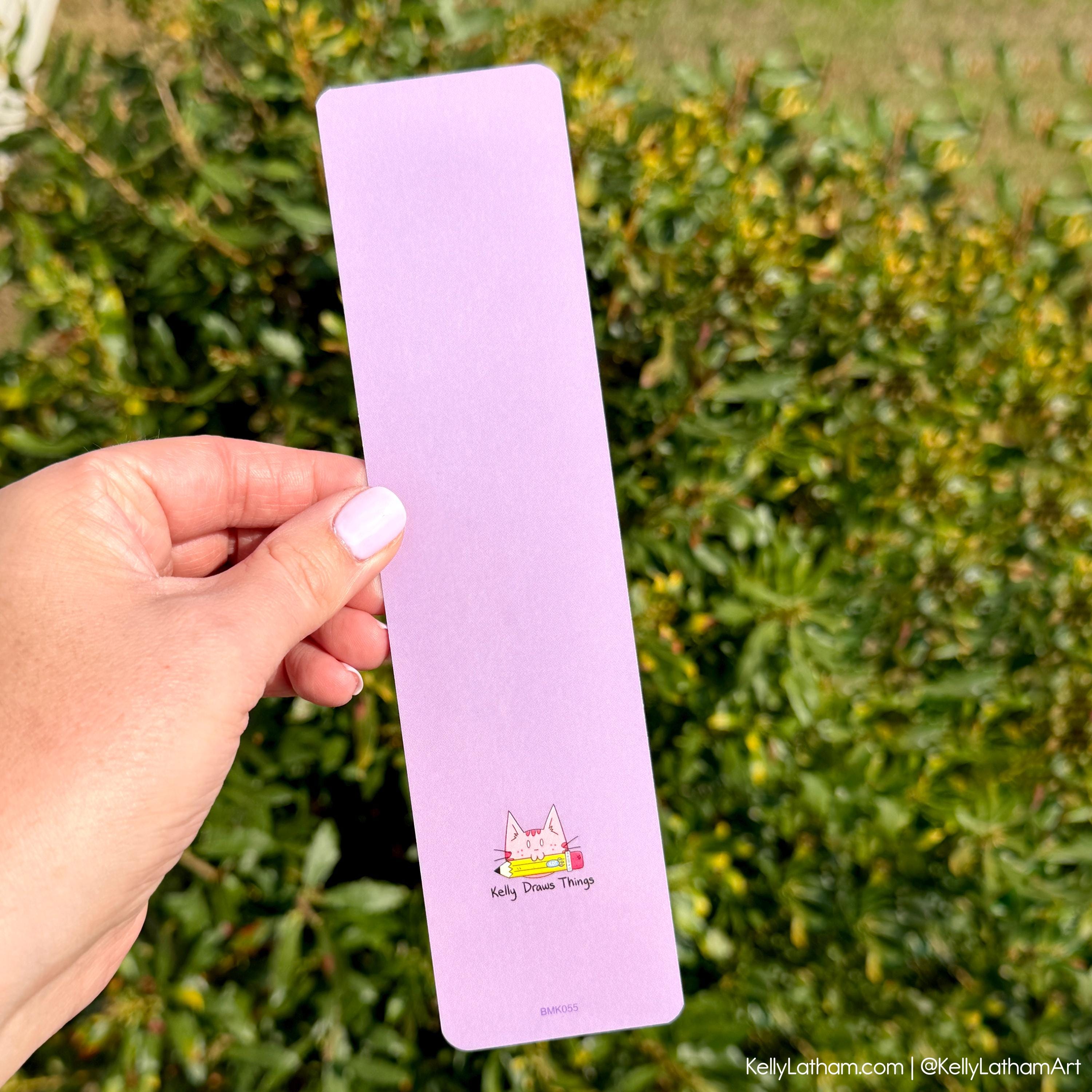 Hand holding a purple rectangular product with a cartoon character against a green leafy background