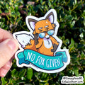 A hand holds a die-cut sticker featuring a cartoon orange fox wearing blue-tinted sunglasses with a teal banner that reads “NO. FOX GIVEN.