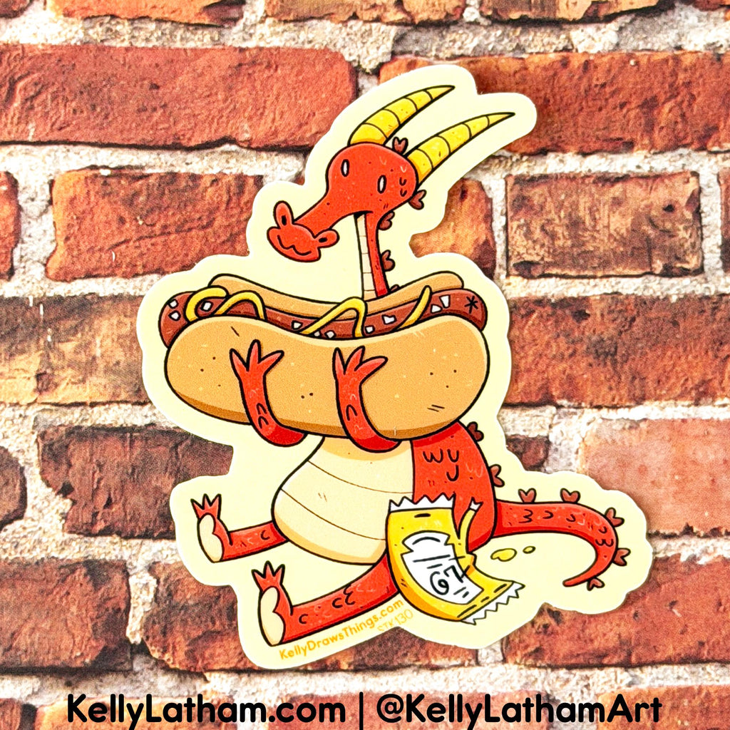 A die-cut sticker featuring a whimsical red dragon carrying a hot dog with mustard and relish, and holding a bag of chips, shown against a red brick wall background. The sticker has a cream border and includes the text 'KellyLatham.