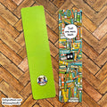 Two book-themed bookmarks laid flat on a wood herringbone floor. One bookmark is solid bright lime green with a small circular cartoon sticker near the bottom.
