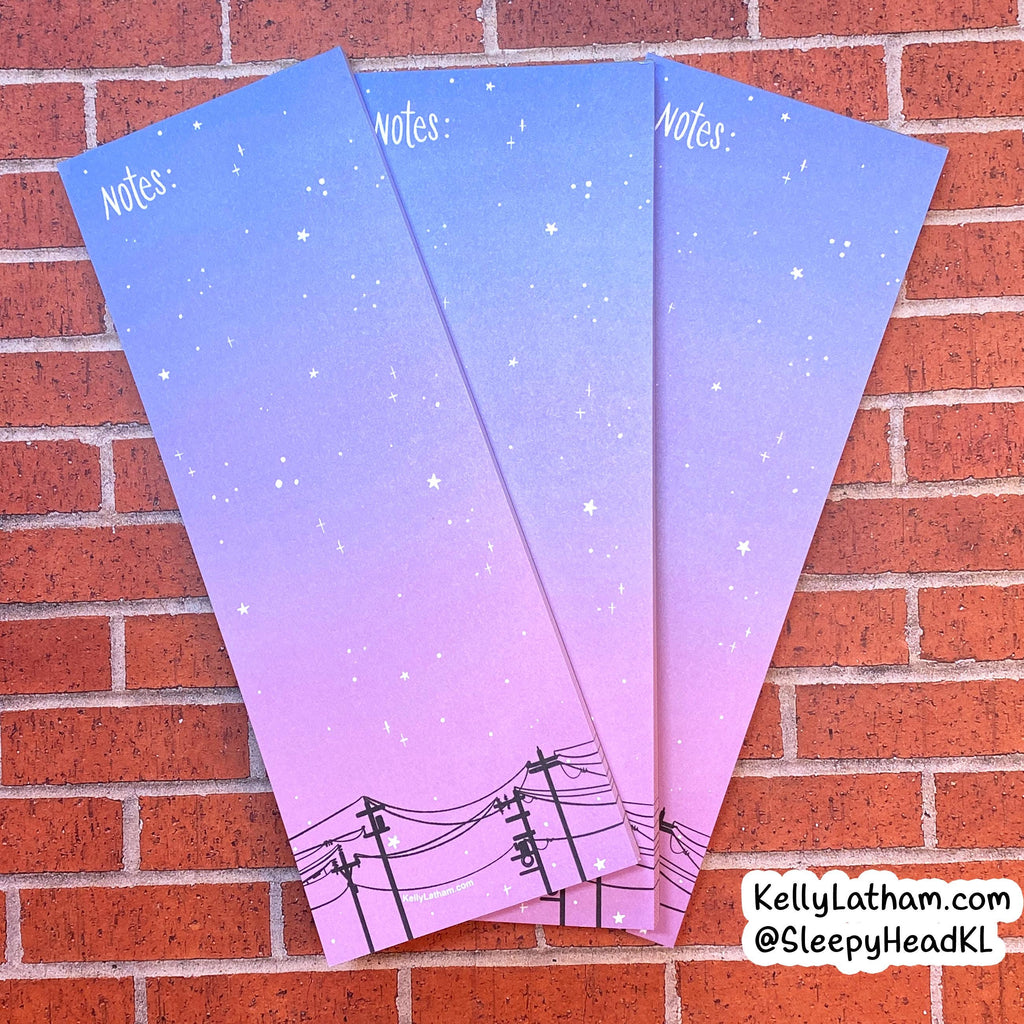 Three pastel gradient notepad sheets with a starry sky and power line design, fanned out on a red brick background.
