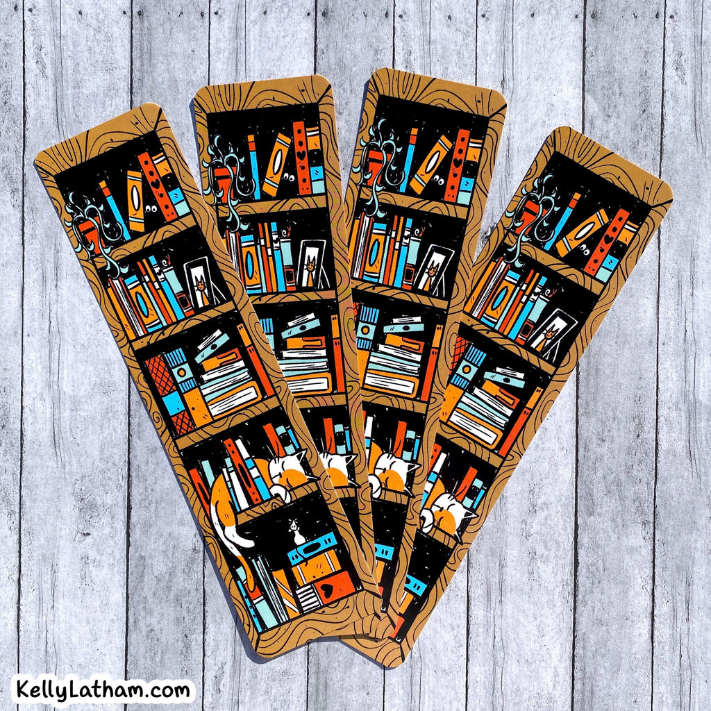 Four decorative bookish bookmarks or tags with a wood-grain border and an illustrated pattern of bookshelves filled with colorful books, arranged on a light gray wood plank background. A small 'KellyLatham.