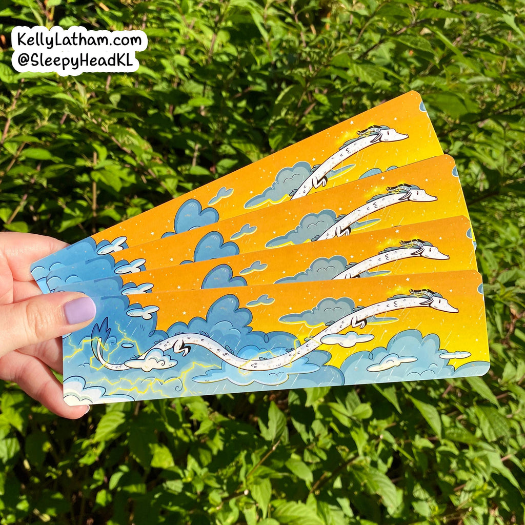 Hand holding a stack of cards with dragon illustrations against a green leafy background