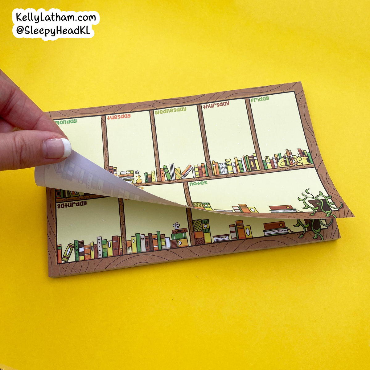 A hand peels back a transparent protective film from a notepad featuring a whimsical bookshelf illustration. The notepad is placed on a bright yellow background, with a brand watermark in the top-left corner.